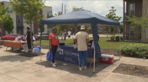 Residents engage with a partner under their blue tent at a community event; Uniting Change with Healthy Partnerships Through Community Engagement & Outreach